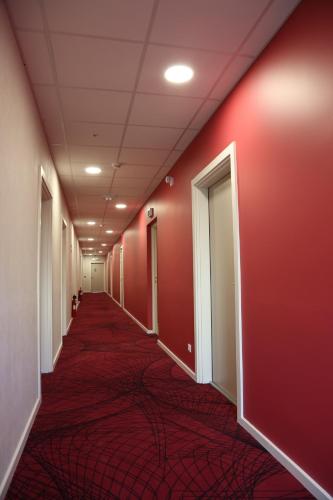 a hallway with red walls and a red carpet at Westlodge Dardilly Lyon Nord in Dardilly