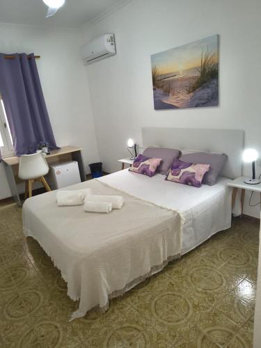a bedroom with a large white bed with purple pillows at Donatella Guesthouse Alicante in Alicante