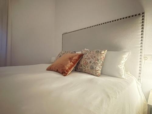 ein weißes Bett mit zwei Kissen darüber in der Unterkunft House of flowers in Mures