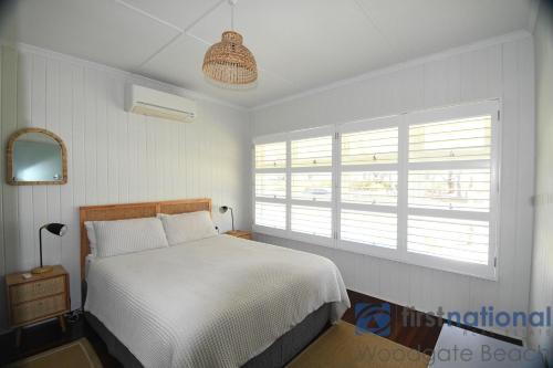 una camera da letto con un letto bianco e una finestra di 1 The Esplanade a Woodgate