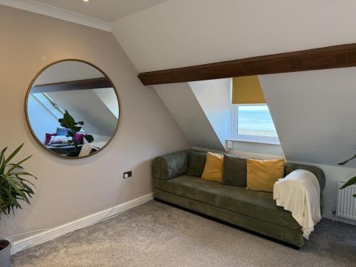 a living room with a green couch and a mirror at Coastal Nest in Margate