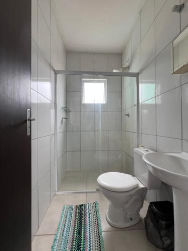 ein weißes Badezimmer mit Toilette und Waschbecken in der Unterkunft Residencial Passos 2 in Guaratuba