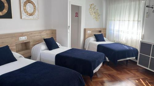 una camera d'albergo con due letti con lenzuola blu di PR Una Estrella Dorada a O Pedrouzo