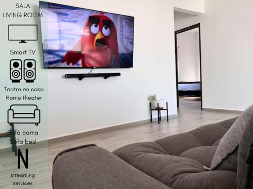 a living room with a couch and a tv on the wall at Increíble departamento en Juriquilla Qro in Juriquilla