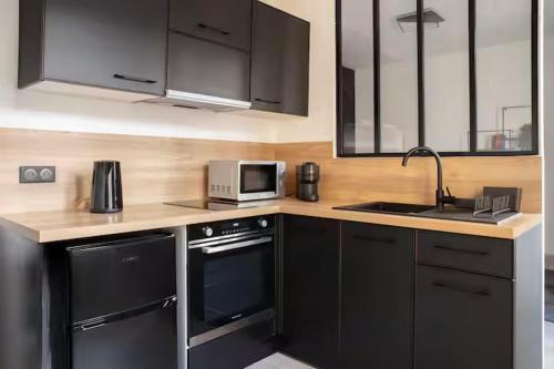 eine Küche mit schwarzen Geräten und einer Arbeitsplatte in der Unterkunft Clair de Lune - Stade de France - Netflix in Aubervilliers