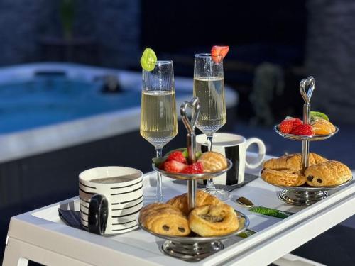 un plateau de pâtisseries et des coupes de champagne sur une table dans l'établissement Suite SPA PRIVÉE, à Portet-sur-Garonne