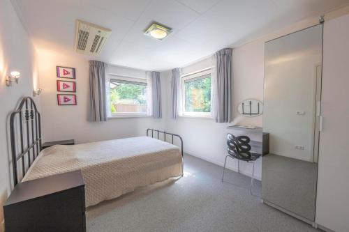a bedroom with a bed and a desk and two windows at Jonkerstee 21 - Ouddorp in Ouddorp
