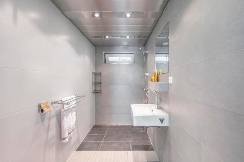 a white bathroom with a sink and a mirror at Jonkerstee 21 - Ouddorp in Ouddorp
