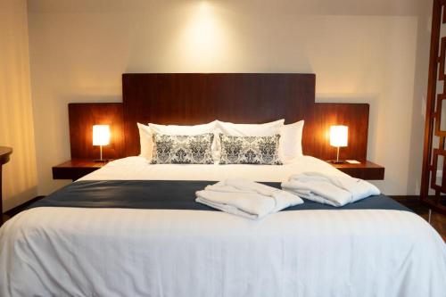 Un dormitorio con una gran cama blanca con dos lámparas. en Parc Royal Suites Hotel, en Cuenca
