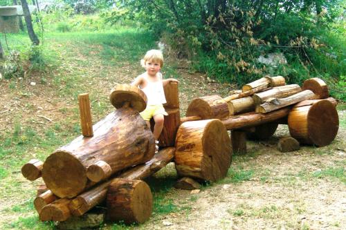 a young boy sitting on a wooden log train at Maso Salim Relax Apartments in Drena