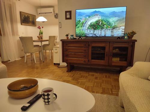 ein Wohnzimmer mit Fernseher und Tisch in der Unterkunft Garden House in Sarajevo