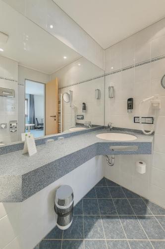 a bathroom with two sinks and a large mirror at AR Boutique Hotel Mannheim in Mannheim