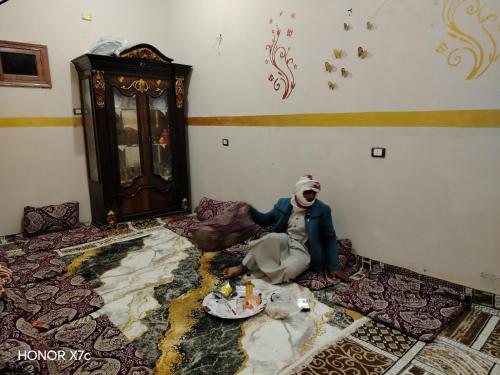 uma boneca sentada no chão de um quarto em البيت السيوي em Oásis de Siuá