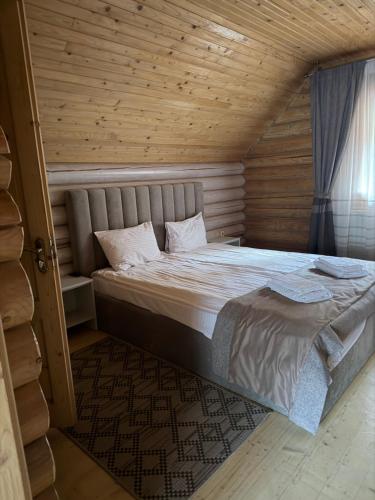 a bedroom with a large bed in a wooden room at Котедж "Villa Затишна" in Mykulychyn