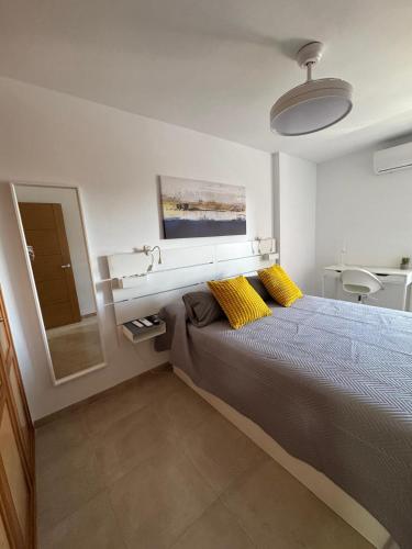 a bedroom with a bed with yellow pillows and a mirror at Minerva 211 - 24h reception - 1 bedroom in Benalmádena