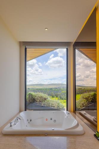 eine Badewanne in einem Zimmer mit einem großen Fenster in der Unterkunft Casa Raíces Hotel Luxury & Viñedo in Los Galvanes