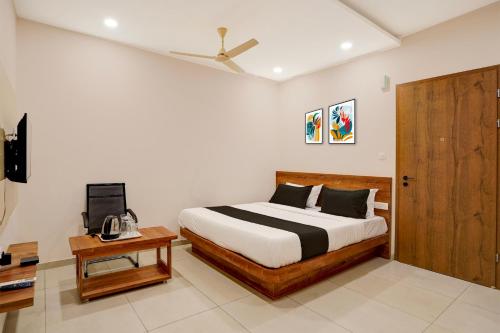 a bedroom with a bed and a wooden door at Hotel O The Classic Crown in Jālahalli