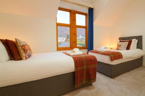 two beds in a room with a window at Ben View Guesthouse in Fort William