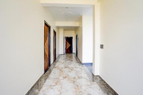 un corridoio con pareti bianche e pavimento in marmo di SPOT ON Hotel Bella Vista a Jhinjhak