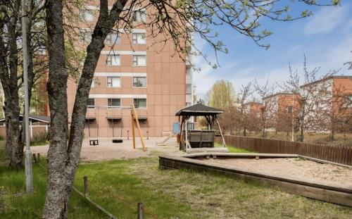 a playground with a gazebo in front of a building at Tapulikaupunki Apartment Helsinki in Helsinki