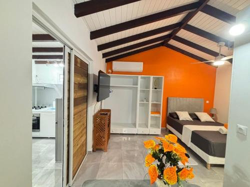 a living room with a bed and orange walls at L'Abri BEAUCI- TURLET in Goyave