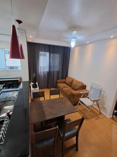 una sala de estar con una mesa y un sofá en Family Flat PG - Praia, Musica e Gastronomia, en Praia Grande