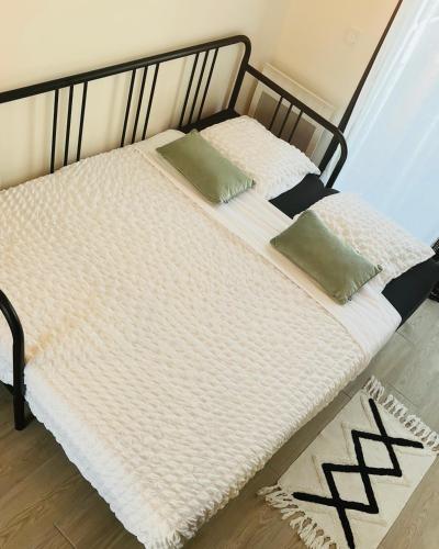 two beds with white sheets and green pillows at Studio du port avec jardin privé in Saint-André-de-Cubzac
