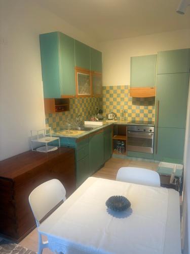 ファーノにあるLa Casa di Annaの緑のキャビネットとテーブルと椅子のあるキッチン