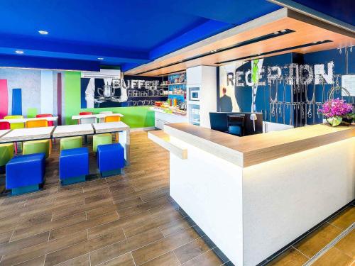 a restaurant with colorful chairs and a reception counter at ibis Budget - Melbourne Airport in Melbourne