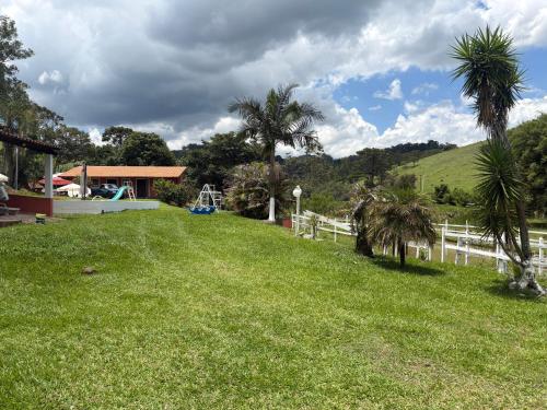 エストレーマにあるSítio do Beto Extrema MGのヤシの木と白い柵のある庭