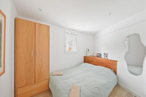 een slaapkamer met een bed en een houten kast bij Le petit Sud in Carqueiranne