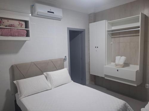 a bedroom with a white bed and a sink at Casa 2 Encanto dos Mares in Itapema