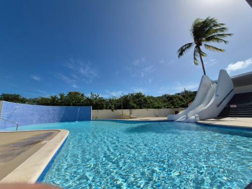 a swimming pool with a slide and a palm tree at Sea Breeze Villa in Fajardo