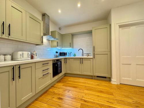 a kitchen with white cabinets and a wooden floor at Longsands Beach Apartment 1 Tynemouth Free Onsite Parking in Tynemouth
