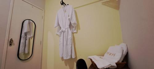 Espaço do acalanto- Quarto em apartamento compartilhado في ناتال: رداء أبيض معلق على جدار بجوار مرآة