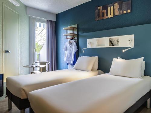 two beds in a room with blue walls at ibis budget Saint-Ouen-l'Aumône in Saint-Ouen-lʼAumône