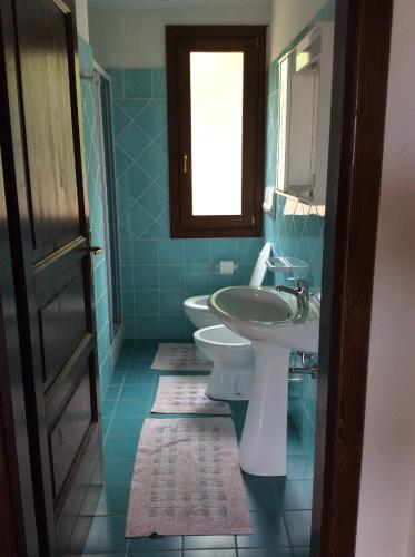 bagno con lavandino, servizi igienici e finestra di Casa Vacanze Residence I delfini a Badesi