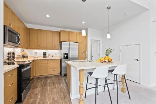 a kitchen with wooden cabinets and a white island with bar stools at Marbella Lane - Elegant 3BR w Marvelous Views in Waianae