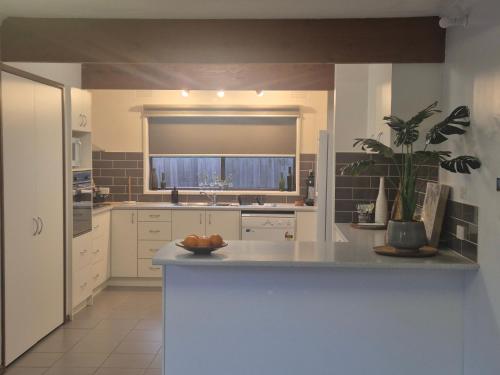 a kitchen with white cabinets and a counter with a plant at Retro Revival - Fondue, Flares & Feeling Groovy in Ocean Grove