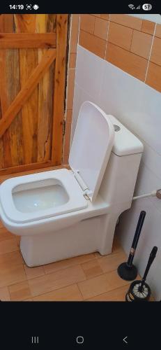 a white toilet in a bathroom with a wooden door at Nanja Mara Lodge in Masai Mara
