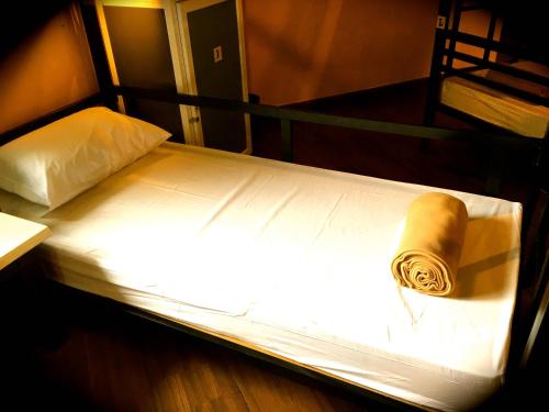 a bed in a room with a roll on it at Urban Hostel Bangkok in Bangkok