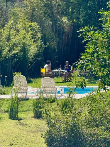 a group of people sitting at a table by a pool at Cabañas Rincon del Champa in San Javier