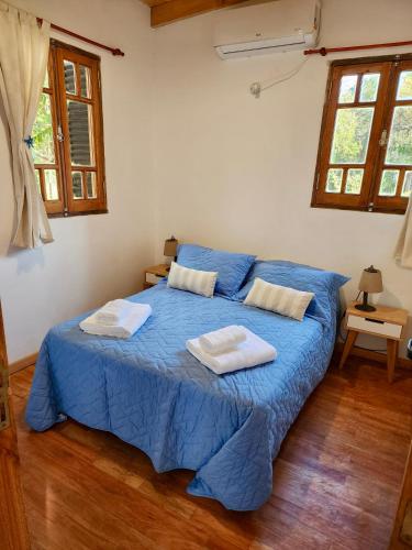 a bedroom with a blue bed with two towels on it at Cabañas Rincon del Champa in San Javier