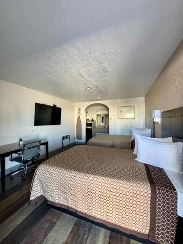 a hotel room with two beds and a desk at Kermit Inn in Kermit