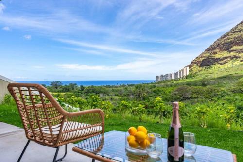 ein Tisch und ein Stuhl mit einer Flasche Wein und Obst in der Unterkunft Marbella Lane - 2 master suites MTOcean Views in Makaha Valley
