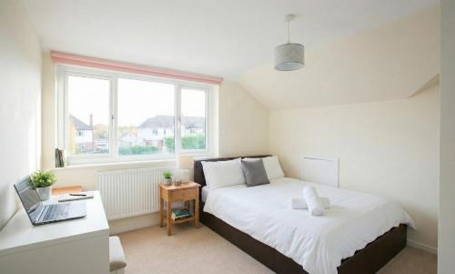 a bedroom with a bed and a desk with a laptop at Grand 5BR Home in Market Harborough with Parking in Market Harborough