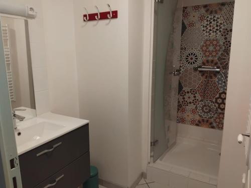 a white bathroom with a sink and a shower at L'appartement d'Ananda in Villefranche-de-Rouergue