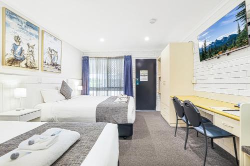 Acacia Motor Inn في بوندابرج: غرفة فندق بها سريران ومكتب