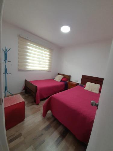 a bedroom with two beds with red sheets and a window at Cabaña Rayantu Antuco in Antuco