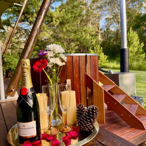 a bottle of champagne on a table with flowers and glasses at Kanimbia Luxury Glamping in Obi Obi